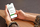 Image of a person sitting, holding their mobile phone while looking at the mental health first aid england course finder website